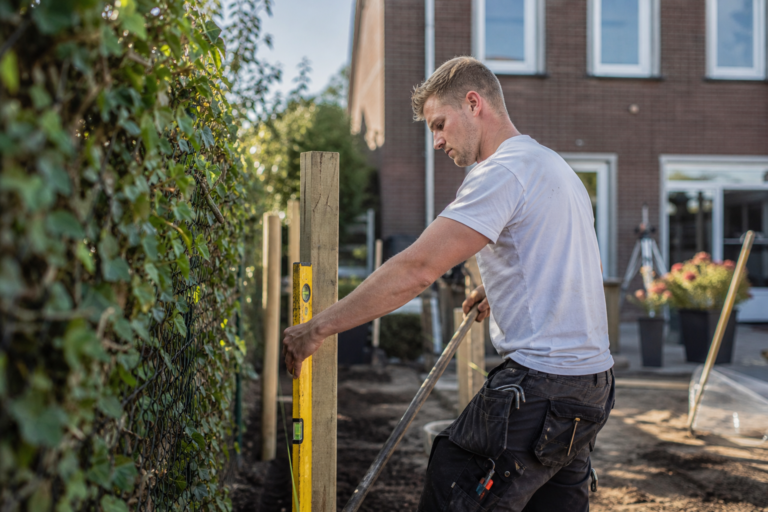 Schutting plaatsen in een tuin met houten palen en schuttingdelen